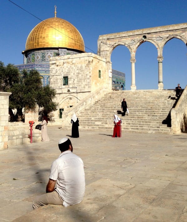 Tamir Mizrachi, who is sitting with his back to the camera, visits Jerusalem's Temple Mount / Noble Sanctuary, a place holy to Jews and Muslims. Israel allows Jews like Mizrachi to visit, but they are not allowed to pray at the hilltop site. Jews pray below at the nearby Western Wall.